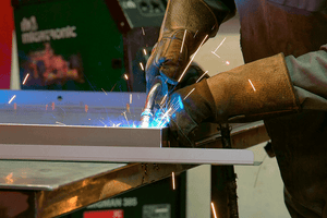 welder works on metal with gloved hands causing sparks